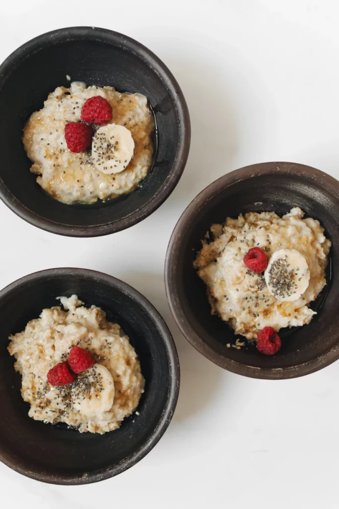 three bowls of oatmeal with bananas and berries.